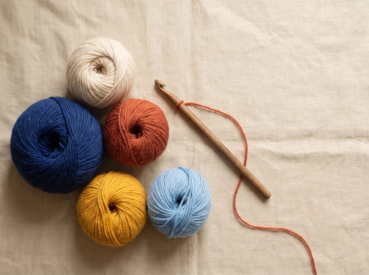 Cinq pelotes de laine aux couleurs de la marque : indigo, écru, terracotta, safran et bleu ciel